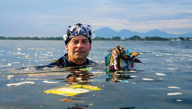Fisk Johnson in the ocean surrounded by ocean plastic