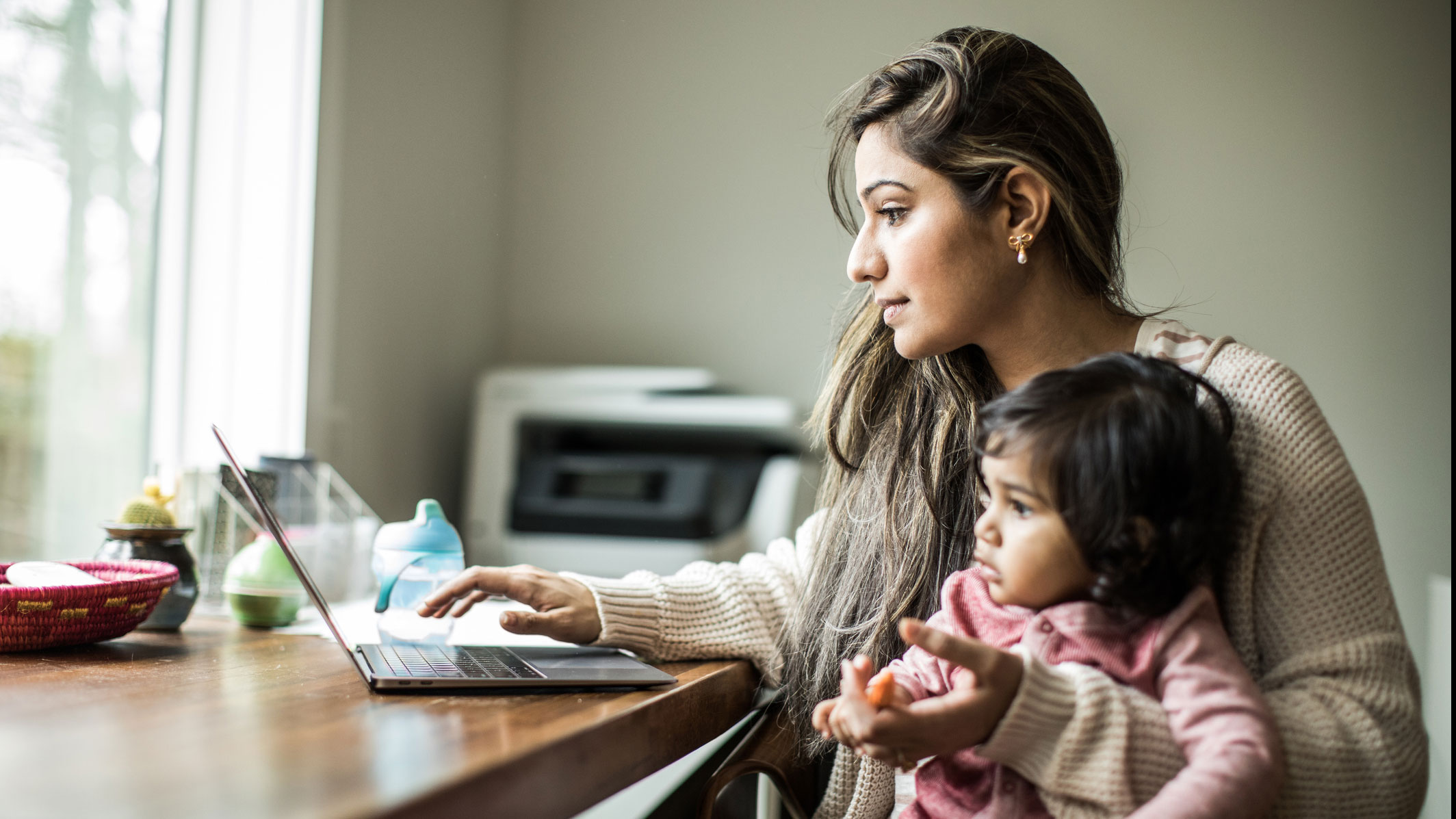 Mother working from home with daughter on her lap