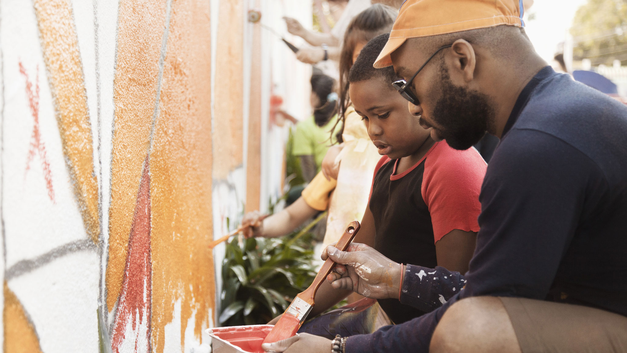 Man helping child paint a wall while volunteering