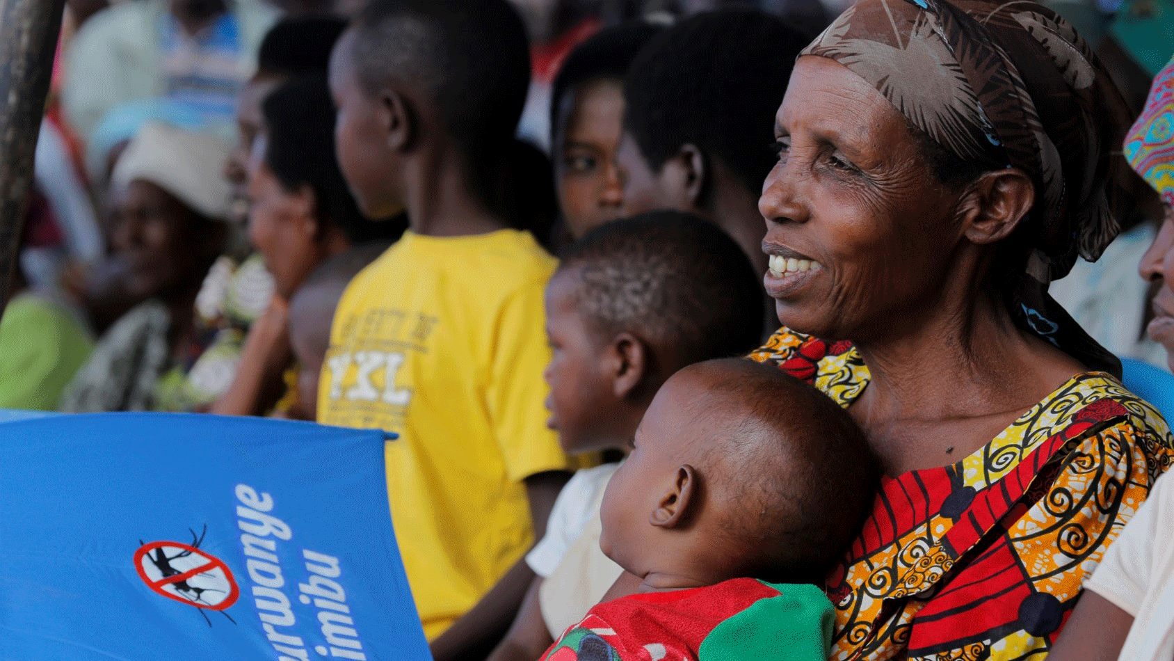 Mother with baby in Rwanda at an educational session on mosquito prevention.